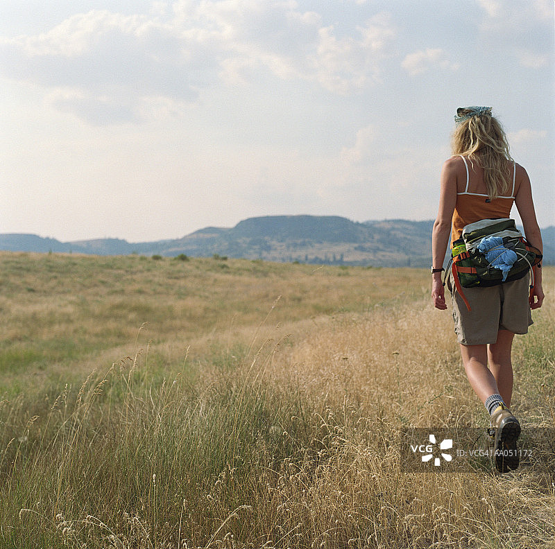 年轻女人在田野中徒步旅行（背影）图片素材