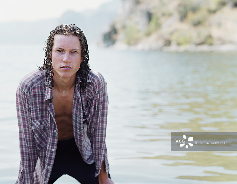 站在湖中，手扶膝盖的年轻男人肖像图片素材