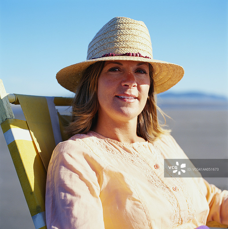 坐在沙滩躺椅上微笑的女人肖像图片素材