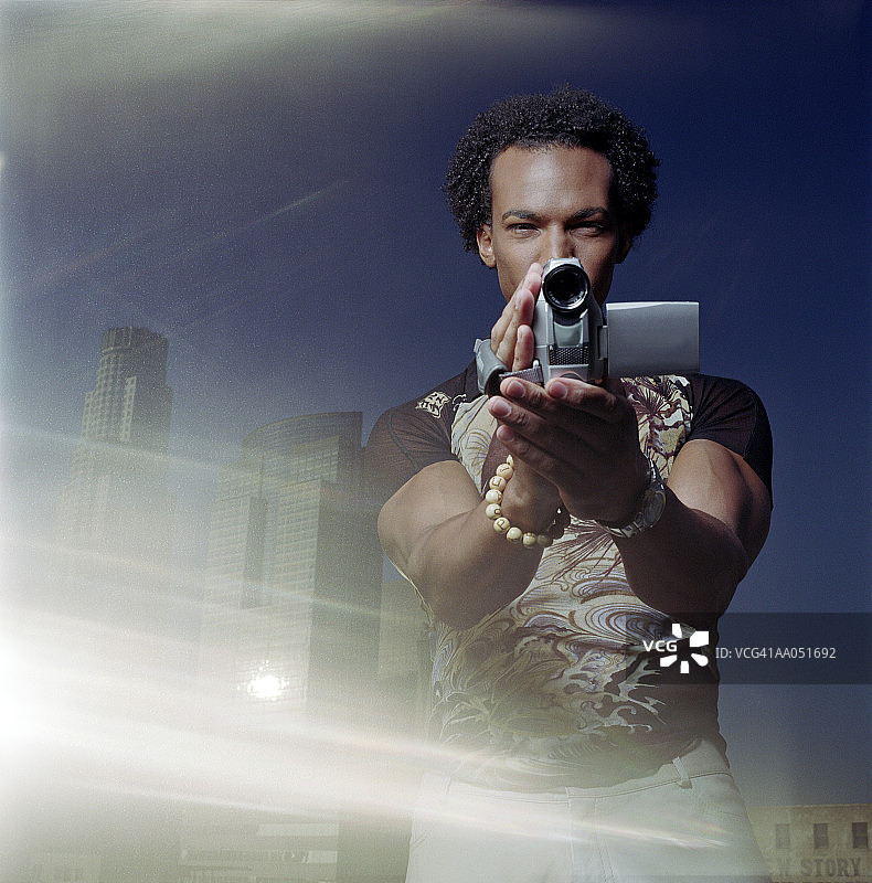 年轻男人在朦胧的阳光下用录像机拍摄图片素材