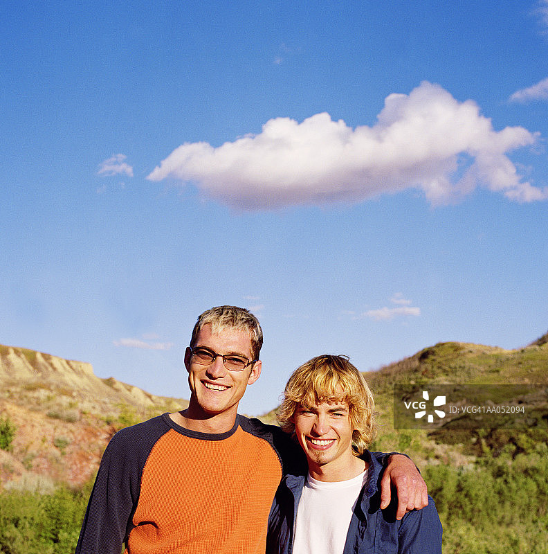 两名年轻男子在加拿大德兰赫勒，手臂互相搂着图片素材