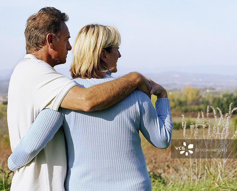 中年夫妇彼此搂着手臂站立，后视图图片素材