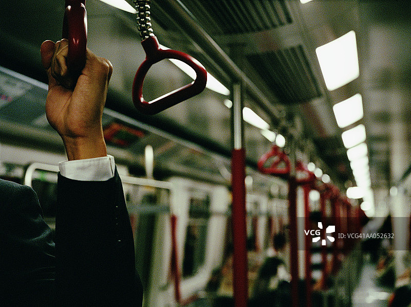 在地铁里抓住扶手的商人，手部特写图片素材
