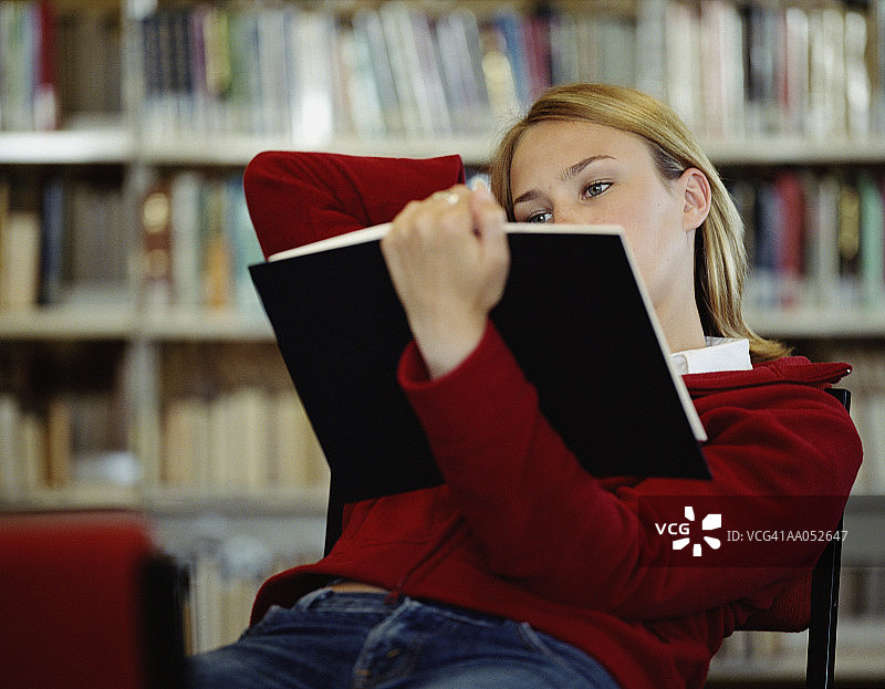在图书馆里斜倚着看书的少女（选择性聚焦）图片素材