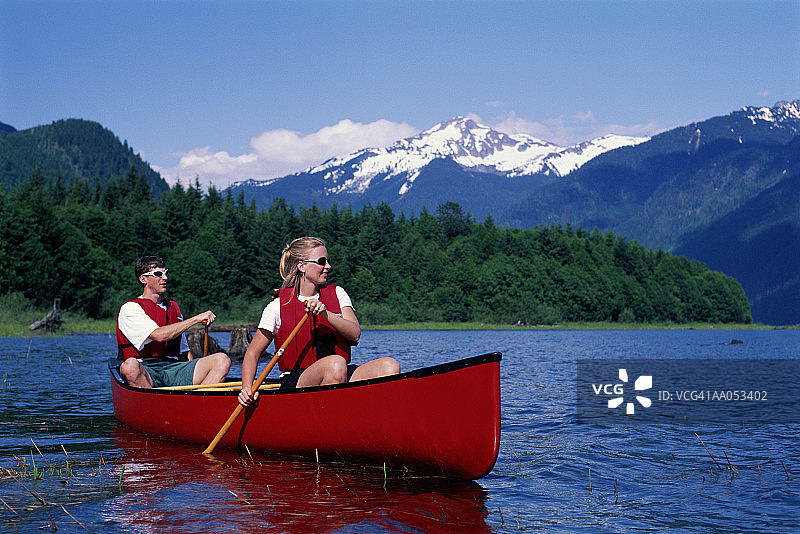 年轻男人和女人划独木舟，地点：美国华盛顿州贝克湖图片素材