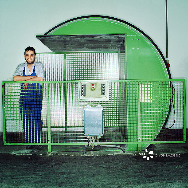 站在造纸机器旁的男人：印刷厂图片素材