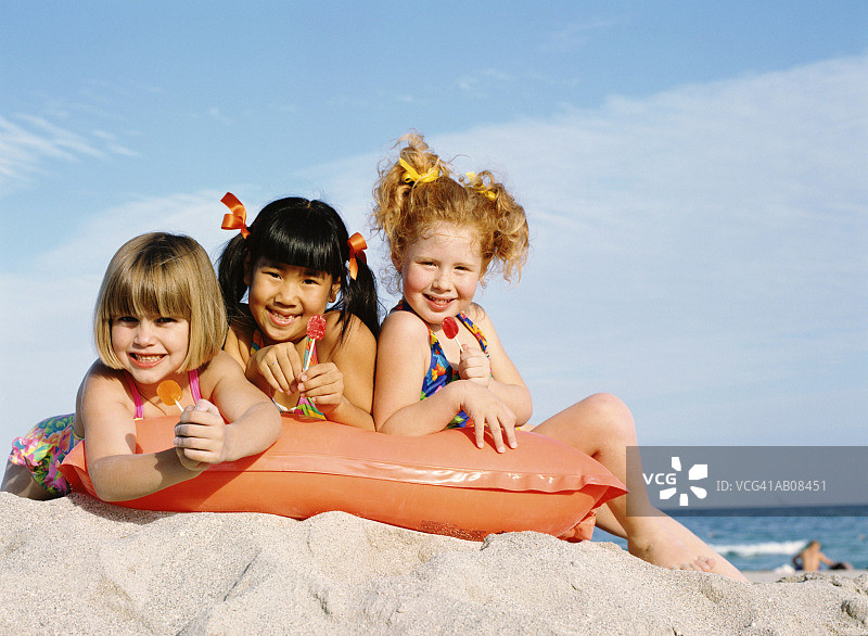 躺在充气泳圈上，拿着棒棒糖的女孩（5-7岁）图片素材