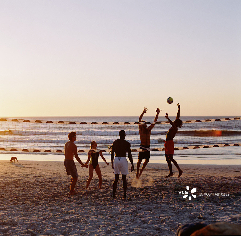 人们在日落时分在海滩上打排球图片素材