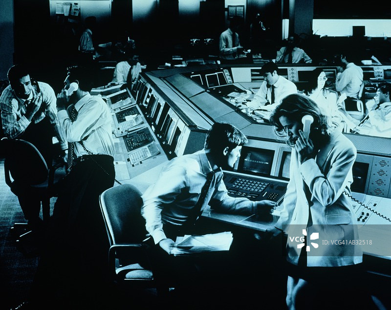 交易室内的交易员在终端工作（蓝色调）图片素材