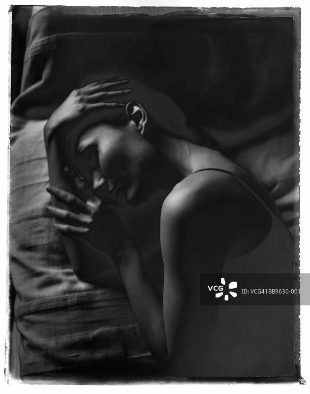 年轻女子躺在床上，手托着头（黑白反色）图片素材