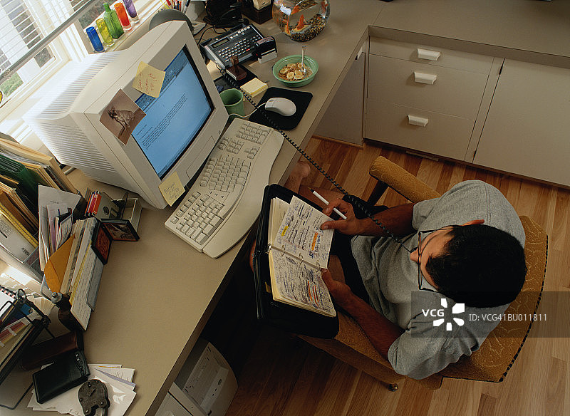 在电脑旁边的日程本上书写的男人图片素材