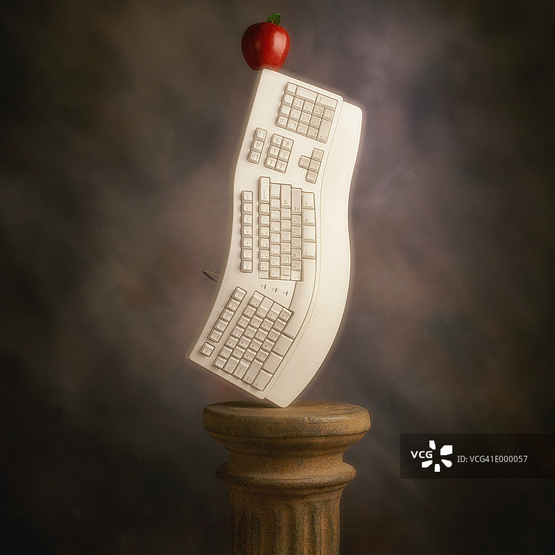 立着的Egrgonomic键盘和顶端的苹果图片素材