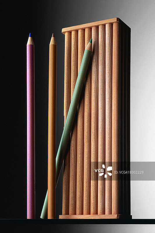 三支彩色铅笔靠在木制铅笔盒上图片素材