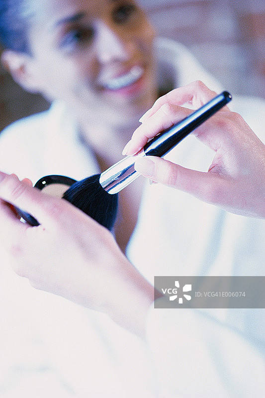 粉饼和刷子，背景中的女人图片素材