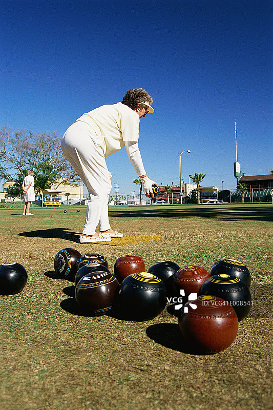 女人在草地滚球比赛中投球图片素材