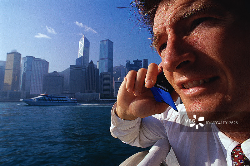 男人在城市背景下手持手机的特写图片素材