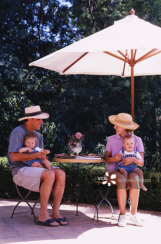 在露台遮阳伞下的家庭图片素材