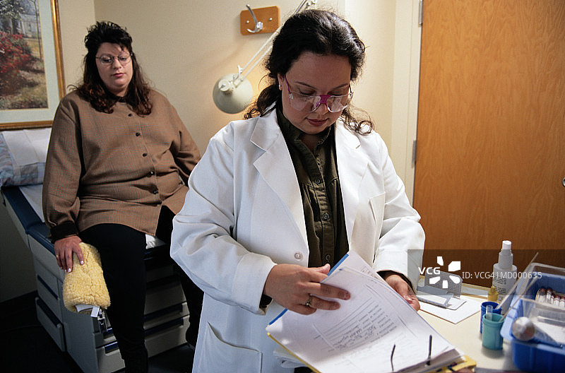 医生阅读妇女的病历图片素材