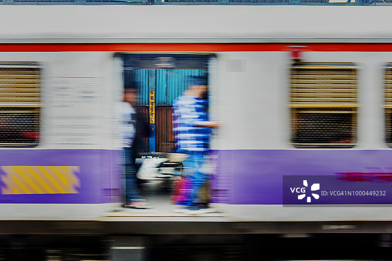 一列载有乘客的行驶中的火车停靠在当地火车站图片素材