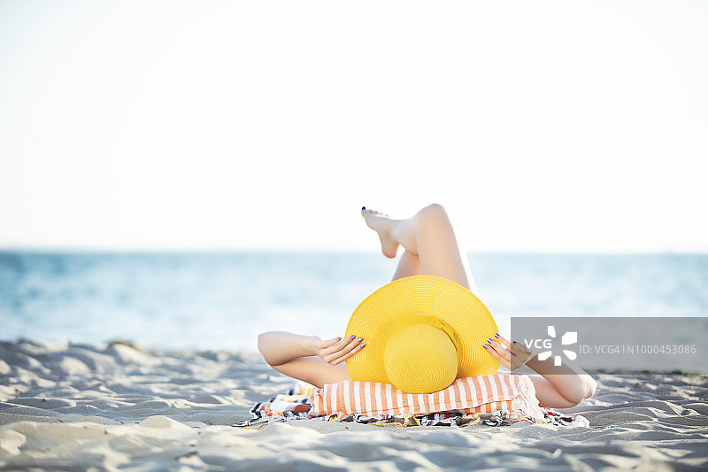 年轻女人在海滩放松日光浴图片素材