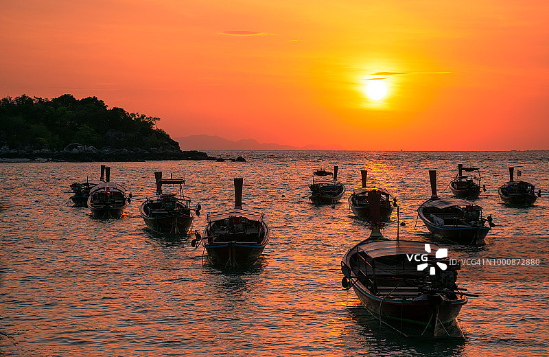 泰国丽贝岛日出时分海滩上的长尾船轮廓图片素材