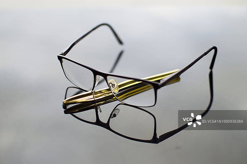 眼镜与金色钢笔的倒影图片素材