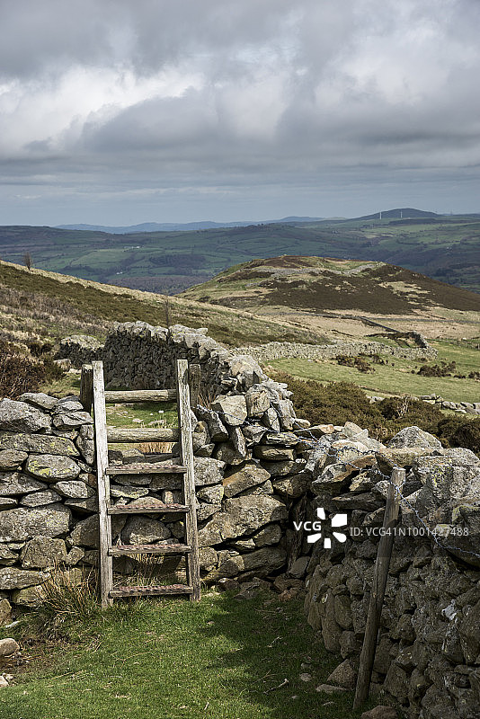 北威尔士山丘上干石墙的木制阶梯图片素材