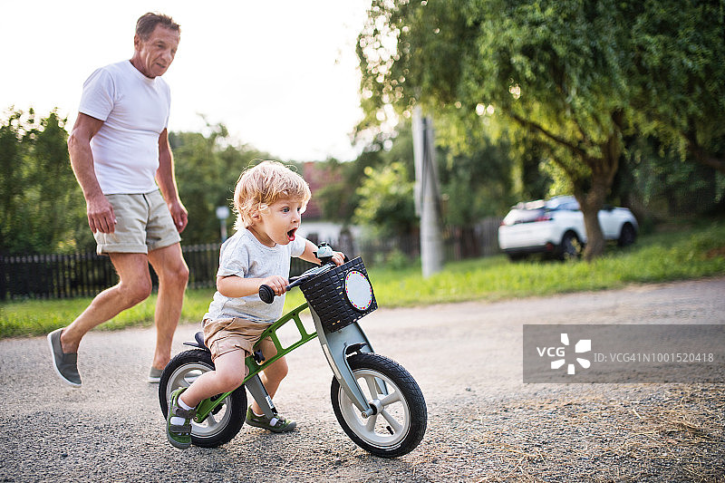 小男孩和他的祖父在户外骑平衡自行车图片素材