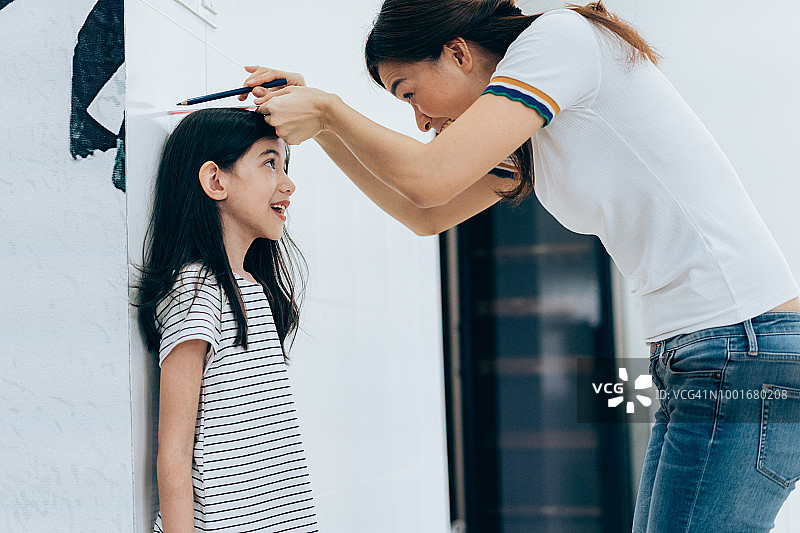 妈妈测量女儿的身高图片素材