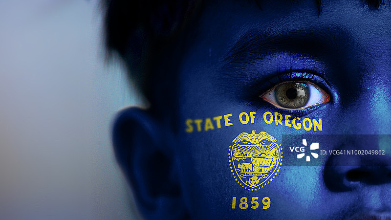 男孩面部特写，看向镜头，面部带有俄勒冈州州旗图案图片素材