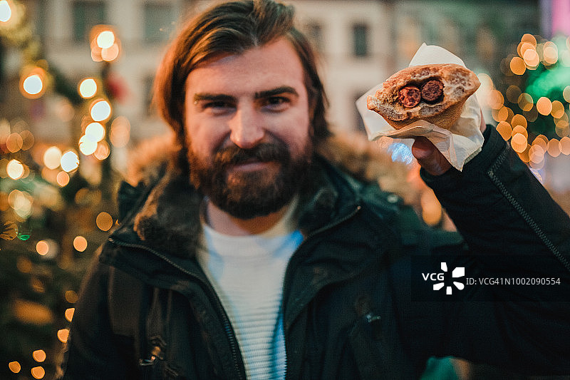 在德国城市街道吃热狗的年轻男人图片素材