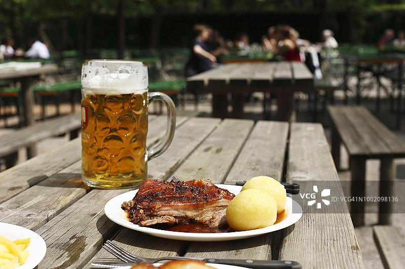 慕尼黑啤酒花园的烤乳猪配饺子和啤酒图片素材