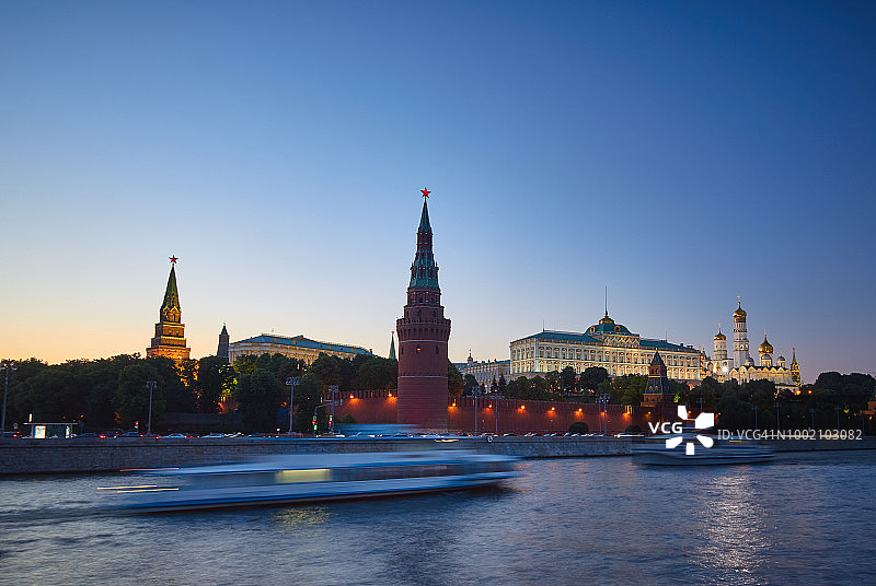 莫斯科克里姆林宫灯光夜景全景，前景为莫斯科河上的游船图片素材