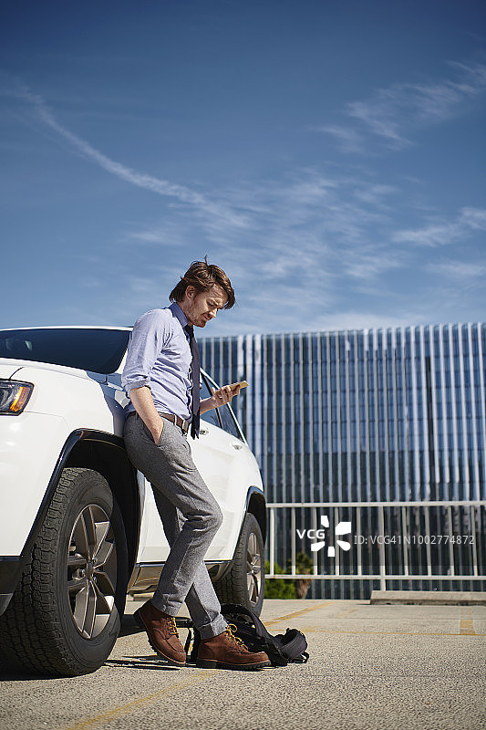 靠在车边看手机的商人图片素材