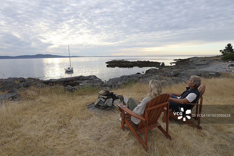 情侣坐在木椅上放松，眺望平静的海面图片素材