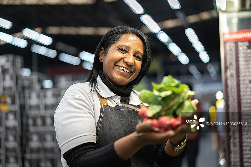 在超市里售货员对蔬菜的照料图片素材