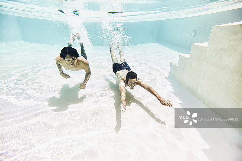 两个男性朋友在游泳池水下游泳的水下视角图片素材