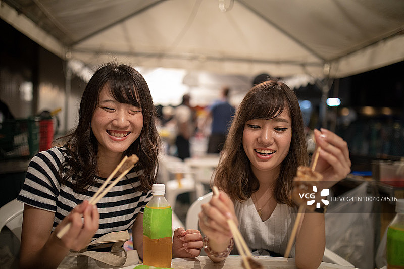 快乐的年轻女性朋友在夜市吃东西图片素材