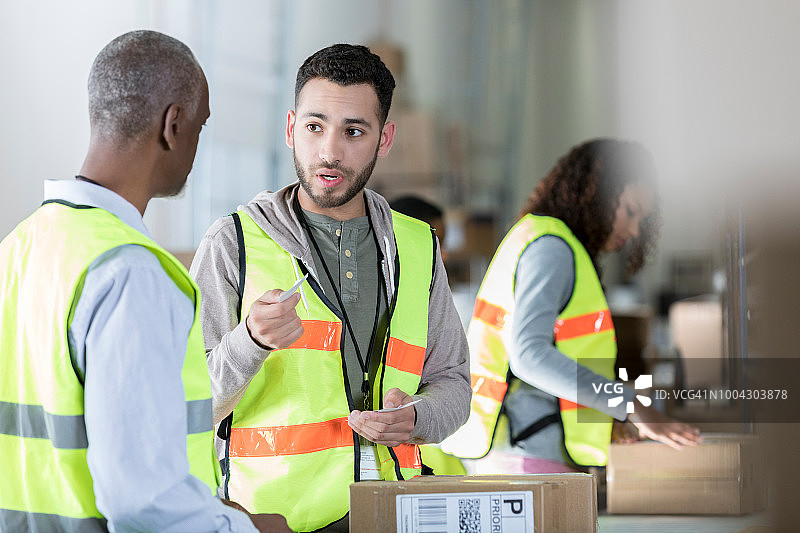 男仓储配送员在工作时讨论事情图片素材