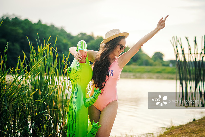 在海滩上拿着泳池漂浮物喝酒的女人图片素材