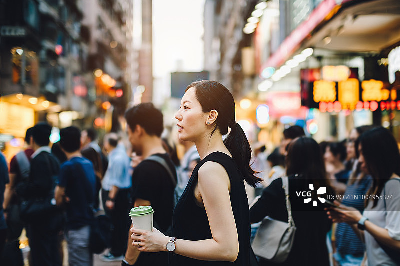 繁华都市街道上端着咖啡的年轻女子图片素材