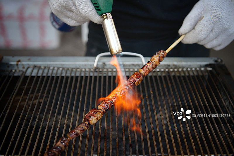 用喷枪烤章鱼串的手图片素材