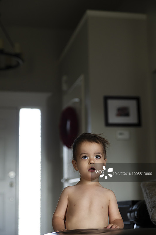 生病幼儿的严肃肖像，他严肃地站着，抬头看着电视图片素材