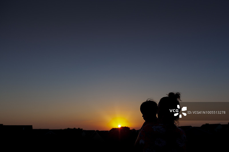 郊区日落时阿姨抱着幼儿的剪影图片素材