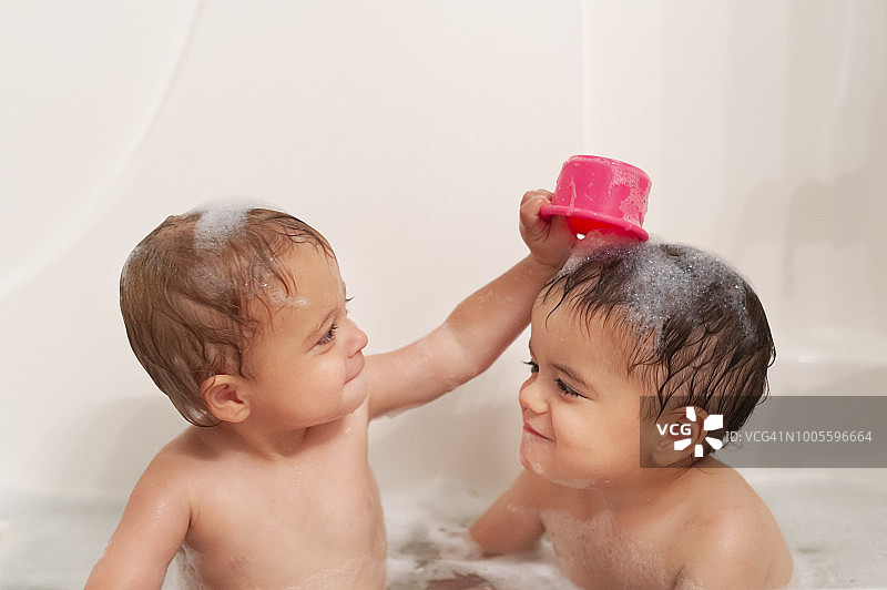 在浴缸里互动的两岁双胞胎男孩图片素材