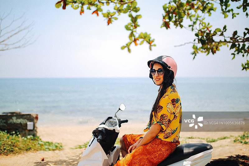 在泰国兰塔岛海边骑复古摩托车休息的年轻女人图片素材
