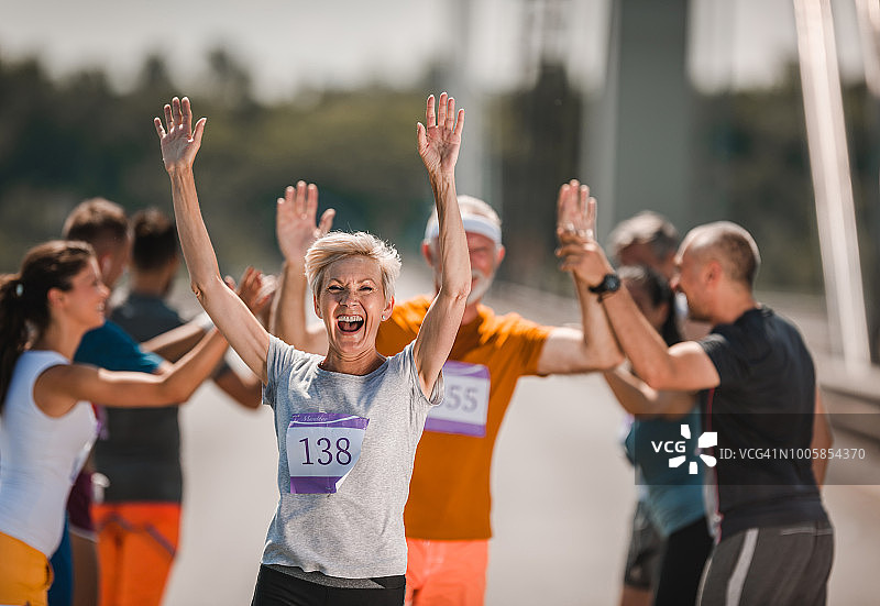 快乐的老年赛跑者在马拉松比赛中向她的支持者们致意图片素材
