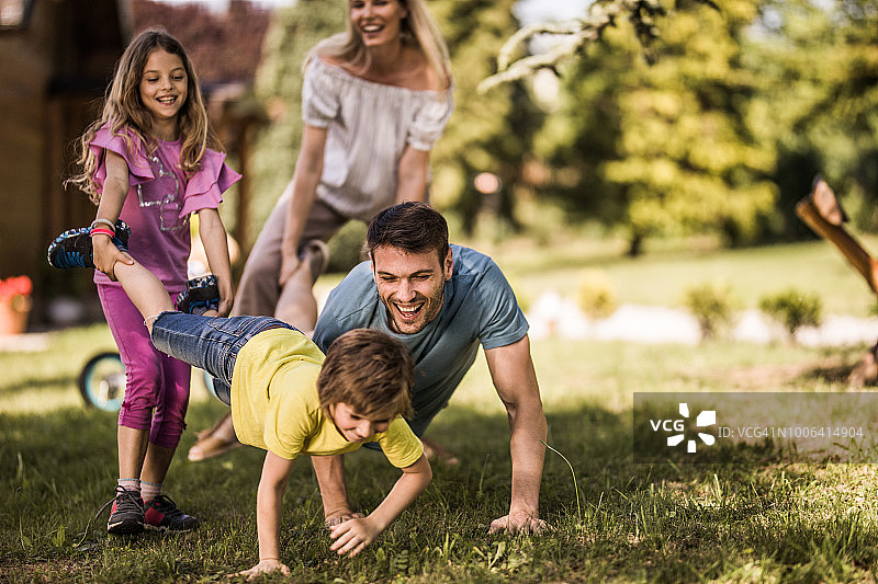 在后院玩独轮车比赛的快乐家庭图片素材
