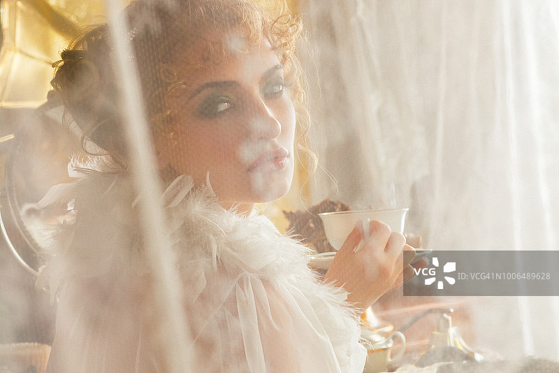 年轻的复古风格女人在早上喝茶或咖啡图片素材