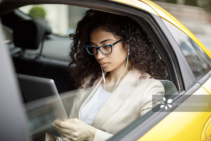 年轻女商人乘坐出租车时使用平板电脑图片素材